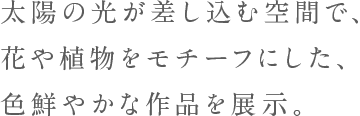 太陽の光が差し込む空間で、花や植物をモチーフにした、色鮮やかな作品を展示。